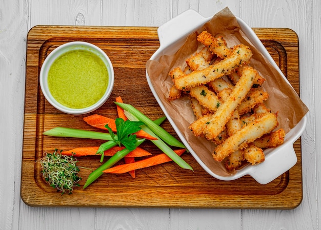 Palitos de pescado con verduras frescas en una tabla de madera