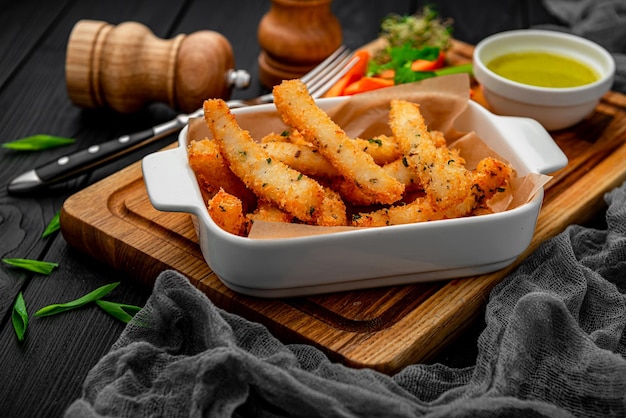 Palitos de pescado con verduras frescas en una tabla de madera