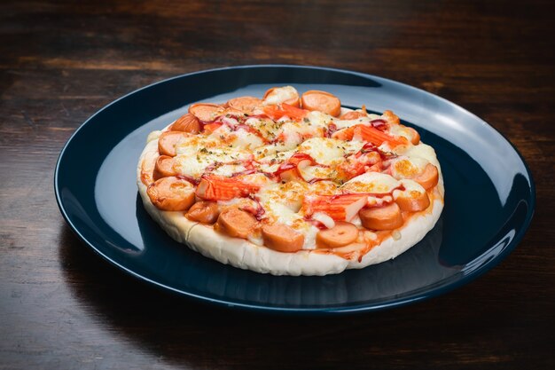 Palitos de pizza, salchicha y cangrejo en un plato de cerámica sobre una mesa de madera.