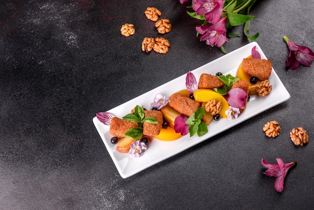 Palitos de queso fresco perfumado con manzana al horno y durazno decorado con flores en un plato blanco