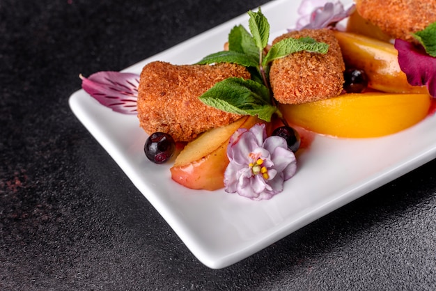 Palitos de queso fresco perfumado con manzana al horno y durazno decorado con flores en un plato blanco