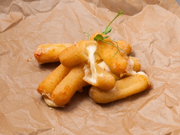 Palitos de queso con mozzarella frita sobre papel artesanal