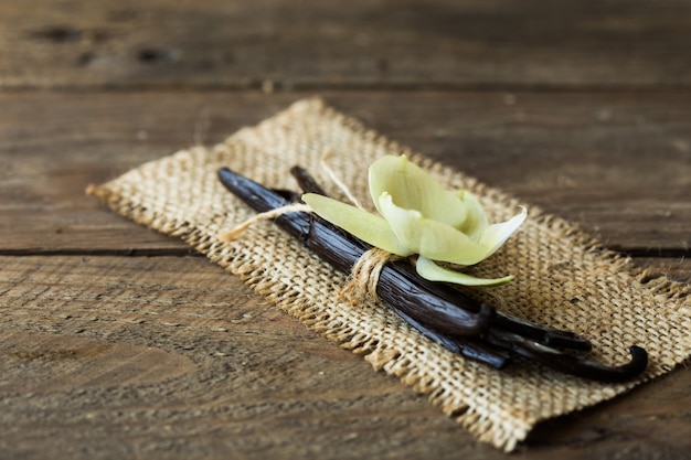 Palitos de vainilla secos y orquídea de vainilla en la mesa de madera. De cerca.