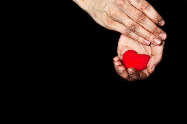 Palma de una campesina con corazón rojo afelpado sobre tela negra. De cerca