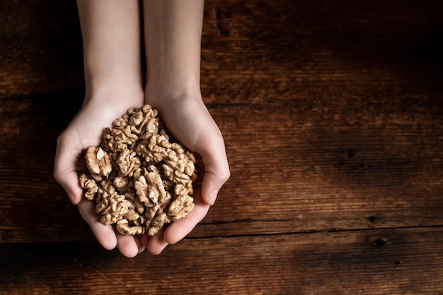 Palmas das mãos das mulheres com nozes Fundo de madeira escura Comida saudável Vegetarianismo Lugar para o seu texto