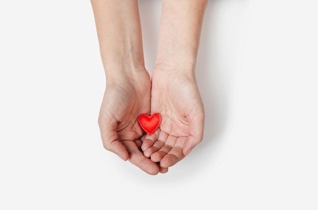 Las palmas femeninas sostienen un pequeño corazón rojo Símbolo de protección del amor