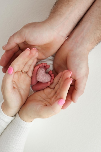 Las palmas de los padres Una madre sostiene los pies de un niño recién nacido en una manta negra sobre un fondo negro Los pies de un recién nacido en manos de los padres Fotografía macro de talones y dedos de los pies