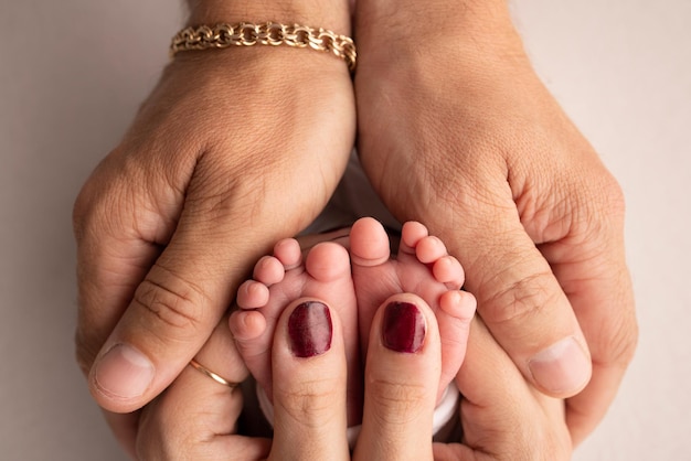 Las palmas de los padres Un padre y una madre sostienen los pies de un niño recién nacido sobre un fondo blanco de estudio Los pies de un recién nacido en manos de los padres Fotografía macro de talones y dedos de los pies