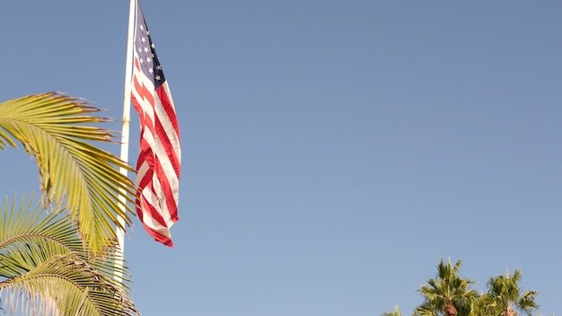 Foto palmeiras e bandeira americana, los angeles, califórnia, eua. estética do verão de santa monica e venice beach. banner star-spangled, stars and stripes. atmosfera de patriotismo em hollywood. velha glória