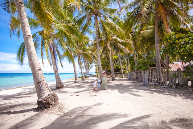 Palmenhain am tropischen Sandstrand mit dreiköpfiger Familie