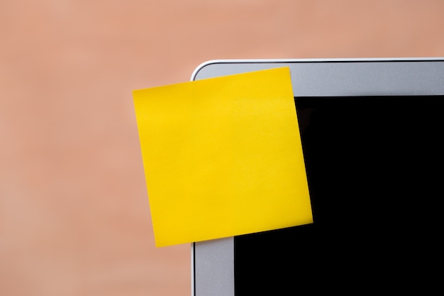 Foto palo de bloc de notas amarillo en blanco con pantalla de ordenador