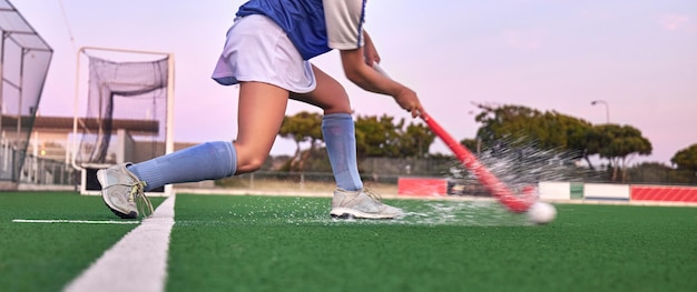 Palo de hockey y pelota con agua salpicada en el césped durante el entrenamiento físico y el entrenamiento físico para una competencia de juegos o un partido Piernas de atleta en el campo deportivo para el desafío de la meta y la batalla