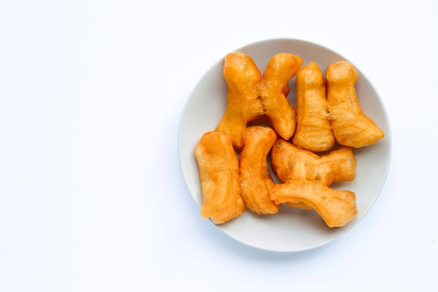 Palo de masa frita, palito de pan chino en un plato blanco sobre una pared blanca con espacio de copia