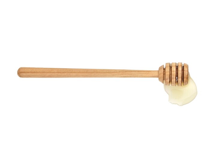 Palo de miel de madera con gota aislado en blanco
