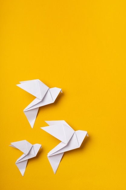 Palomas blancas de origami como símbolo de fe, esperanza y paz en un fondo amarillo