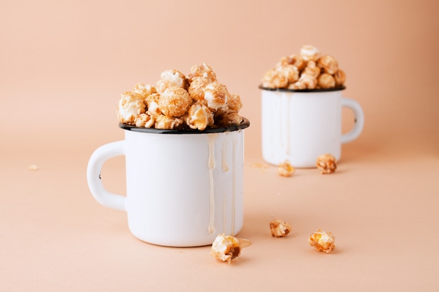 Palomitas de caramelo en copas de metal blanco vintage sobre una pared marrón