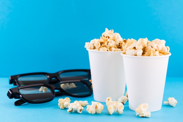 Palomitas de caramelo en vasos de papel y gafas 3D