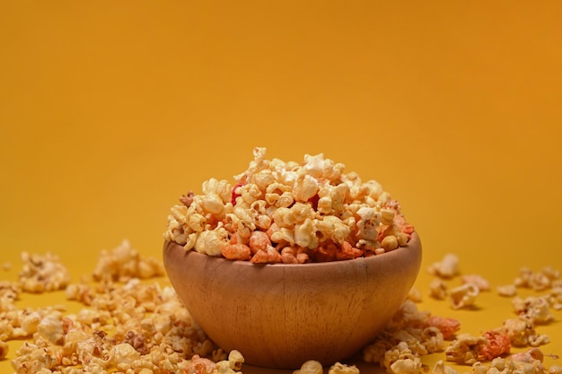 Palomitas caseras en cuenco de madera aislado sobre fondo amarillo