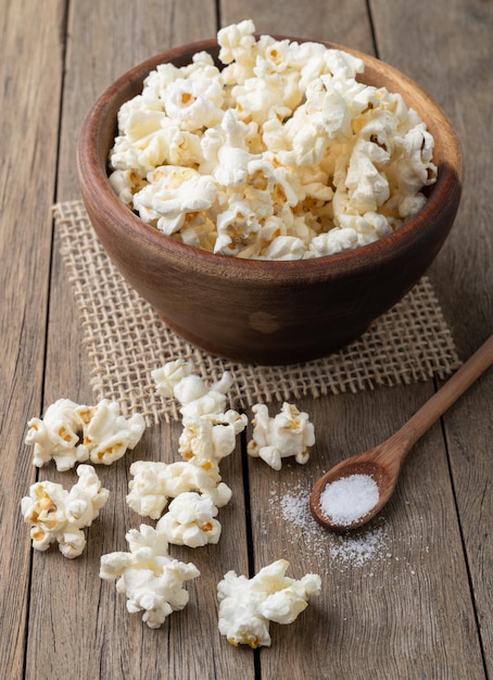 Palomitas de maíz en un bol con sal y soda sobre mesa de madera