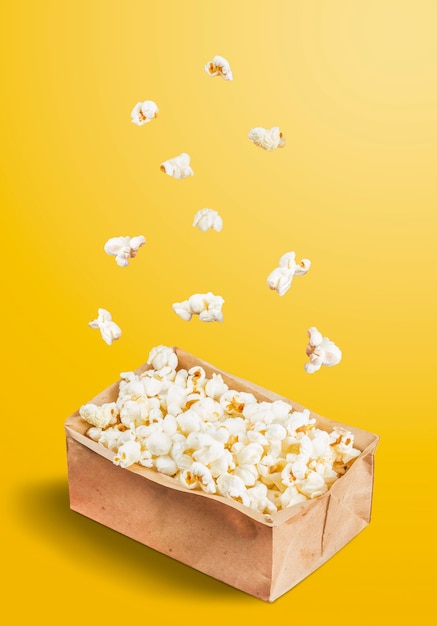 Foto palomitas de maíz cayendo en una olla sobre un fondo amarillo. celebración de junio.