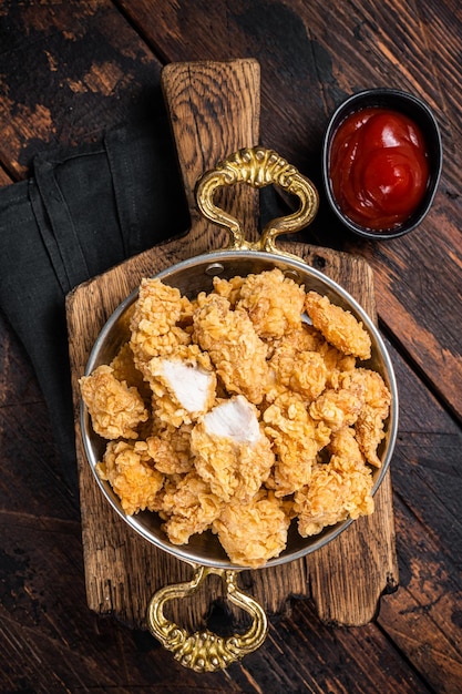 Palomitas de maíz crujientes caseras Bocaditos de pollo en una sartén Fondo de madera Vista superior