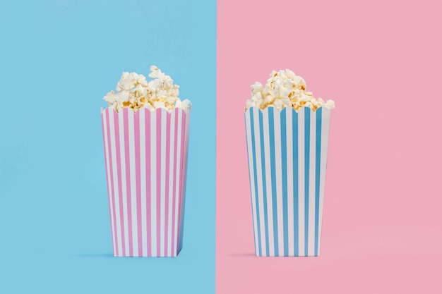 Palomitas de maíz en cubos sobre fondo azul claro y rosa