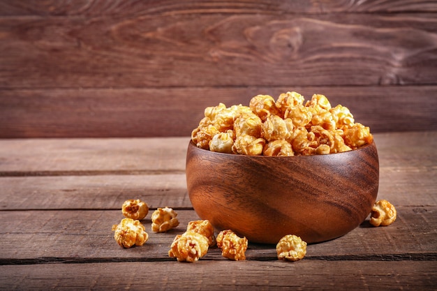 Palomitas de maíz dulce en tazón de madera sobre madera