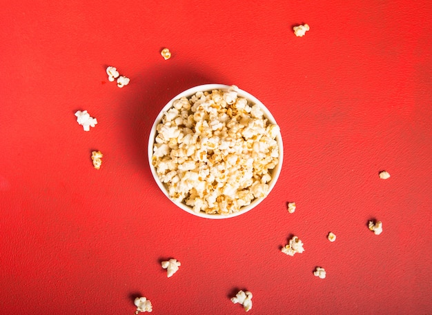 Palomitas de maíz frescas derramadas del recipiente en rojo