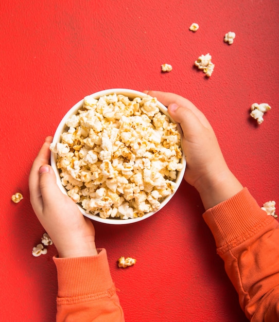 Palomitas de maíz frescas derramadas del recipiente en rojo