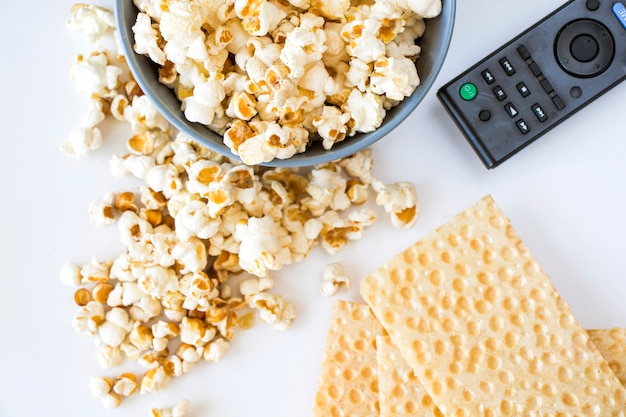 Palomitas de maíz fritas en el fondo blanco y controlador de TV