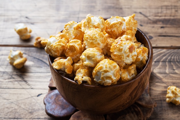 Palomitas de maíz en glaseado de caramelo en placas de madera sobre una mesa rústica.