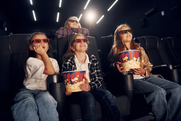 Foto con palomitas de maíz grupo de niños sentados en el cine y viendo películas juntos