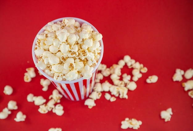 Palomitas de maíz con mantequilla en una taza de palomitas de maíz rojo, merienda en la casa o en el cine