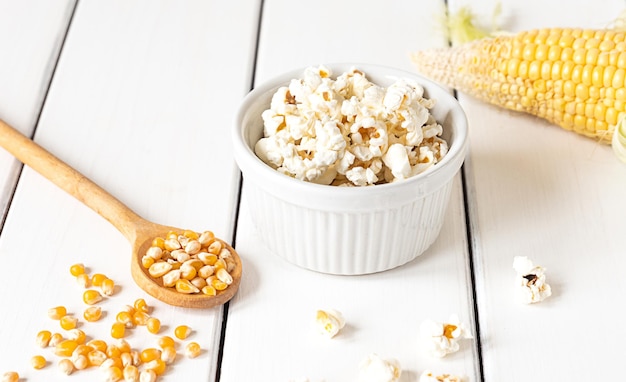 Palomitas de maíz mazorcas de maíz y granos de maíz sobre fondo blanco.