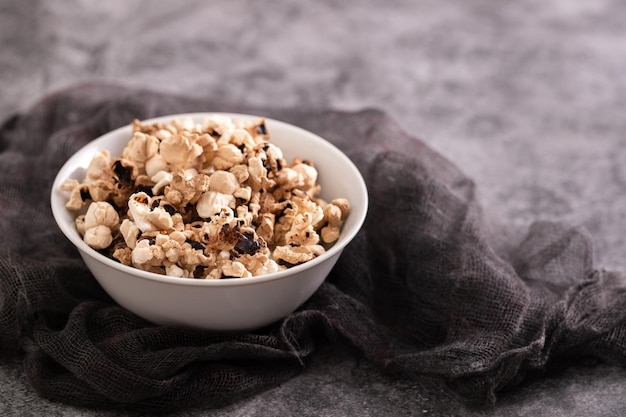 Palomitas de maíz quemadas en el pequeño tazón blanco sobre cerámica