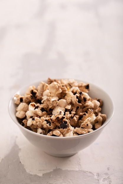 Palomitas de maíz quemadas en el pequeño tazón blanco sobre cerámica