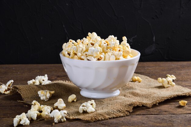 Palomitas de maíz saladas al aire libre. Un tazón de palomitas de maíz en una mesa de madera. Palomitas de maíz en la mesa de madera.