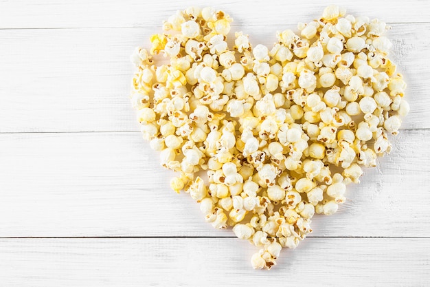 Palomitas de maíz saladas en la forma del corazón en una tabla blanca. Vista superior.