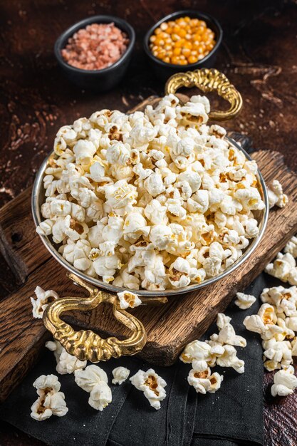 Palomitas de maíz saladas preparadas en una sartén y grano de maíz Fondo oscuro Vista superior