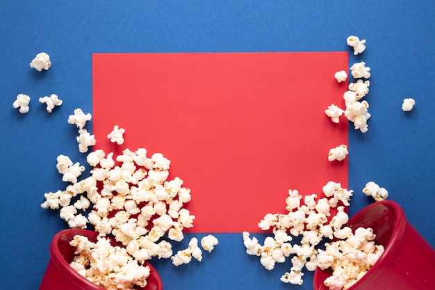 Palomitas de maíz sobre fondo azul y tarjeta roja vacía