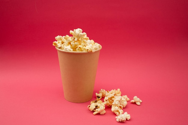 Palomitas de maíz en una taza sobre un fondo rosa brillante