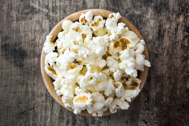 Palomitas de maíz en un tazón en la vista superior de la mesa de madera