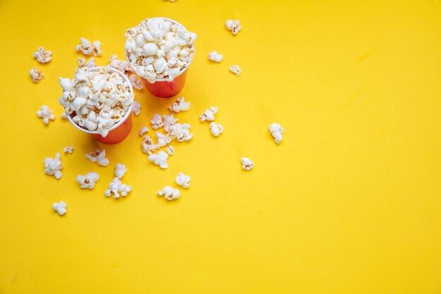 Palomitas de maíz en vasos de papel rojo sobre fondo de color amarillo