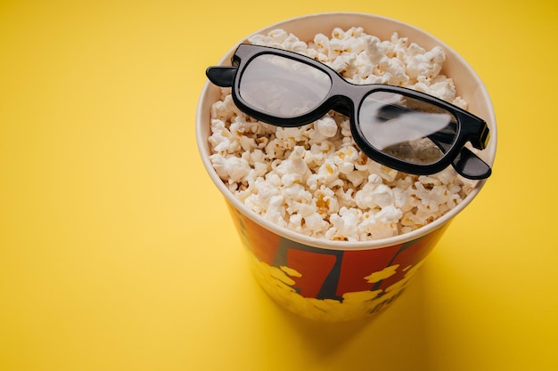 Palomitas de maíz y vasos sobre un fondo amarillo con espacio de copia Vista superior