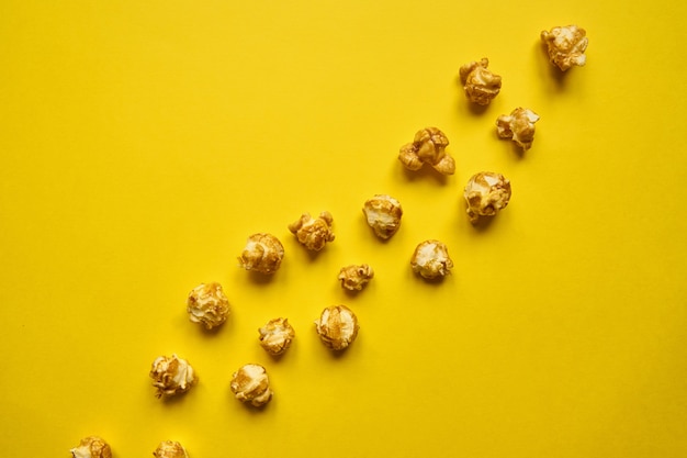 Palomitas de oro con caramelo sobre fondo amarillo.