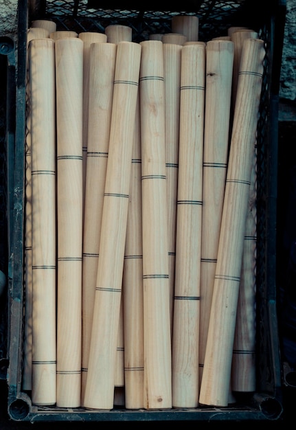 Palos de cilindro de madera en una caja de plástico