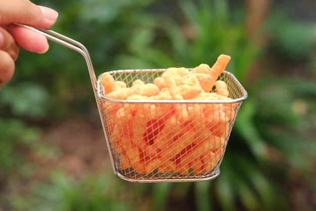 Palos de maíz fritos y crujientes en una canasta sobre un fondo de naturaleza verde