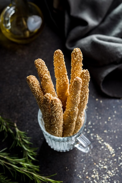 Palos de pan grissini italianos con semillas de sésamo en una taza en la mesa de la cocina