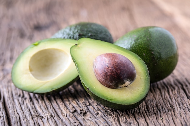 Palta. Cortar el aguacate en una mesa de fondo de madera de roble. Enfoque selectivo.