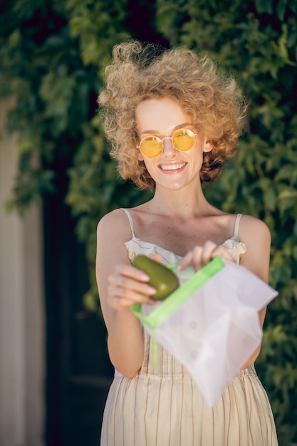 Palta. Una foto de una mujer joven con un aguacate en la mano.